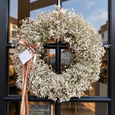 Large handmade dried gypsophila wreath with blush and champagne ribbons on a dark door